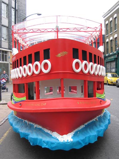 Front view of a red, yellow and blue boat with white circular 'tyre-like' fenders down each side
