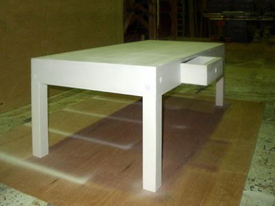 Three-quarter view of a white coffee table with one of its drawers open