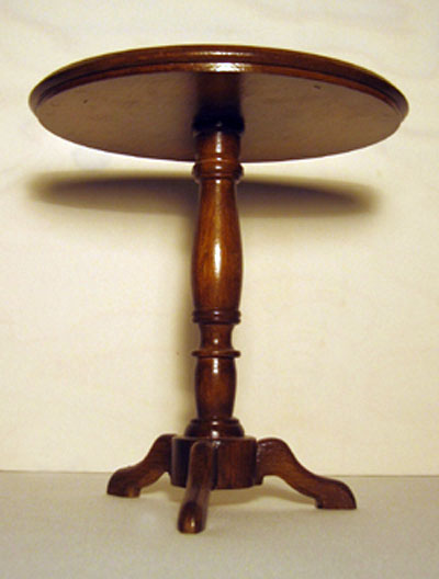 Front view of a round occasional table with a turned support and three small legs