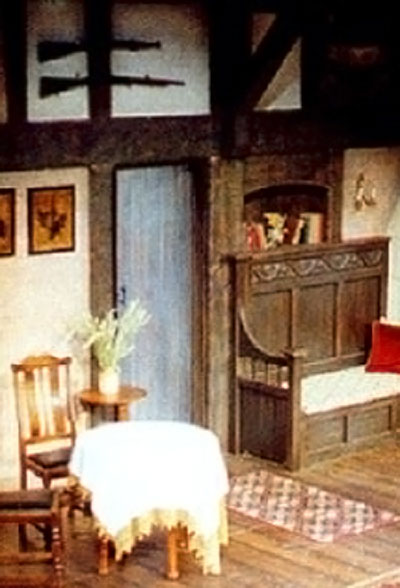 view of stage set - close up detail of a carved settle, wooden beams and door